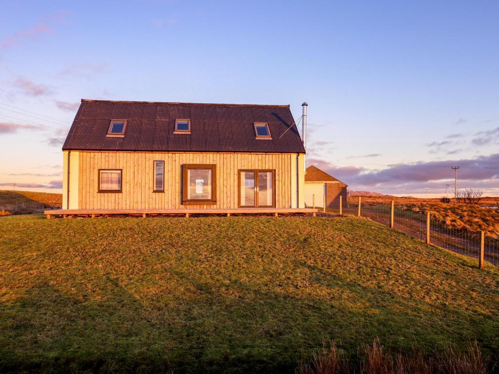 a house on top of a grassy hill at Heatherlea in Carinish