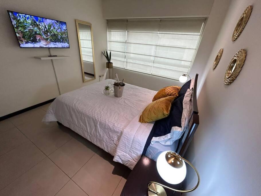um quarto com uma cama e uma televisão na parede em Ecusuites Ejecutiva Torre Sol Aeropuerto IX em Guayaquil