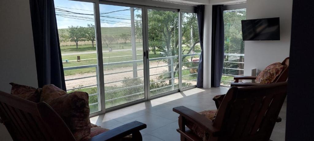 una sala de estar con vistas al campo a través de las ventanas en Alfonsina Holiday Home en Sierra de la Ventana