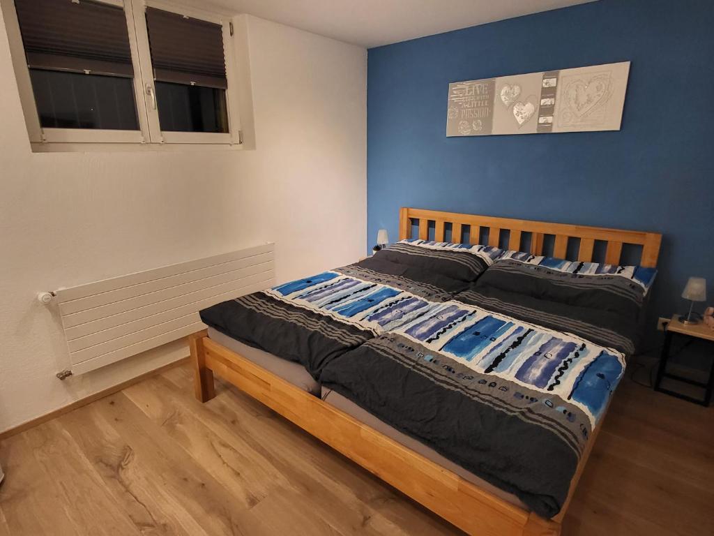 Bett in einem Schlafzimmer mit blauer Wand in der Unterkunft Ahornzimmer, ruhige Lage, nähe Bahnhof und Zentrum in Buchs