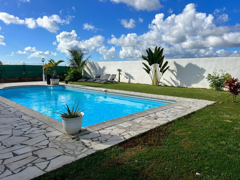 a swimming pool in a yard with a stone walkway at Superbe Villa Bwa Lélé in Rivière-Salée