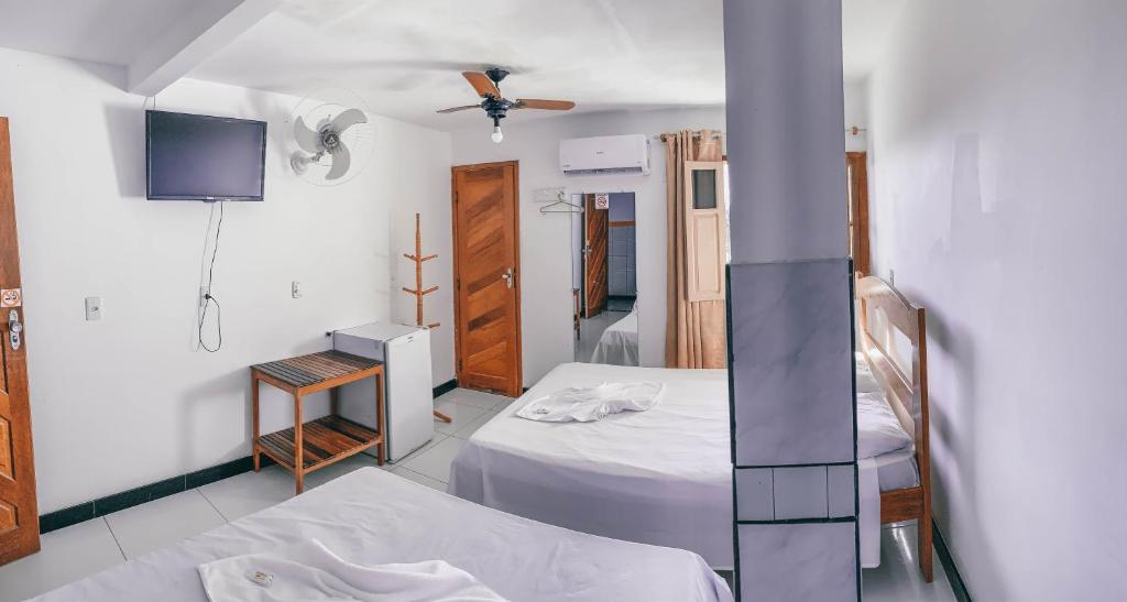 a hotel room with two beds and a tv at Hotel Sanches in São Mateus