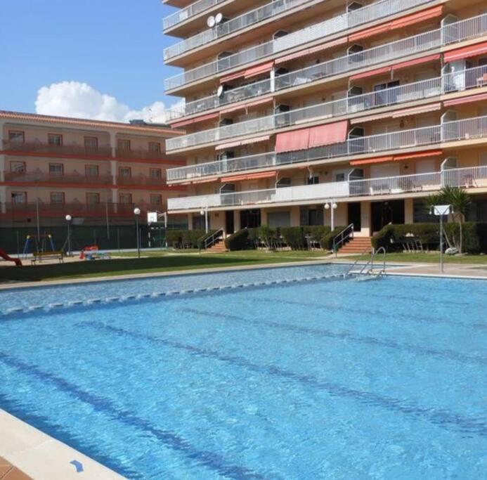 une grande piscine en face d'un bâtiment dans l'établissement Apartamento con gran piscina y frente a la playa., à Malgrat de Mar