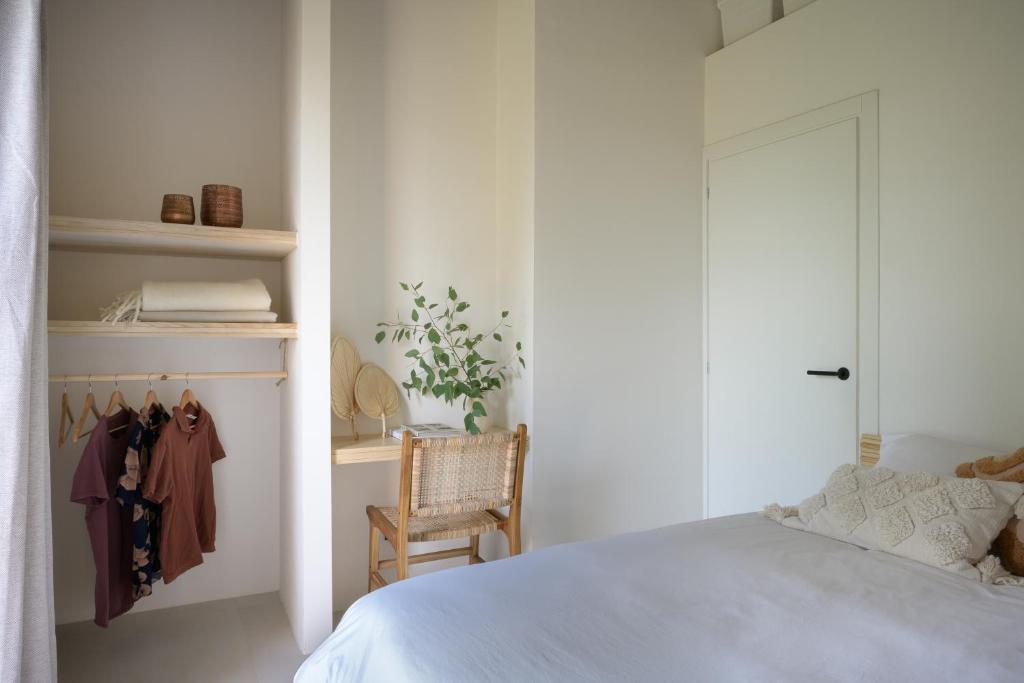 ein weißes Schlafzimmer mit einem Bett und einem Stuhl in der Unterkunft Spereto Pendolino, pool, nature and view in Montaione
