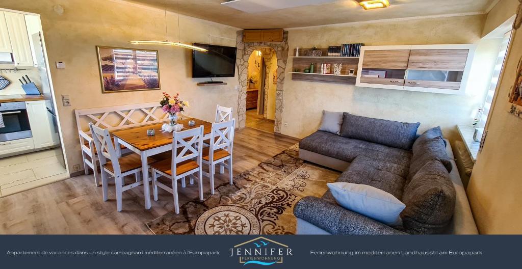 ein Wohnzimmer mit einem Sofa und einem Tisch sowie eine Küche in der Unterkunft Ferienwohnung Jennifer in Rust