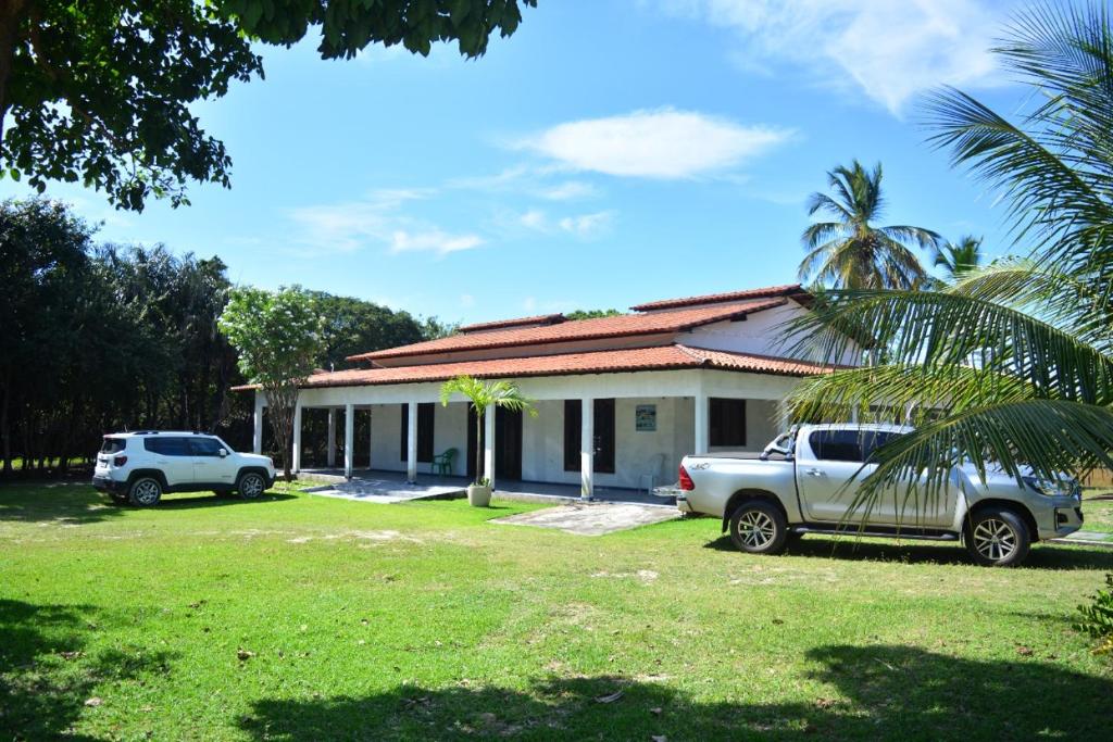 a house with two cars parked in front of it at Pousada Lagoa do Barreiro Azul in Paulino Neves