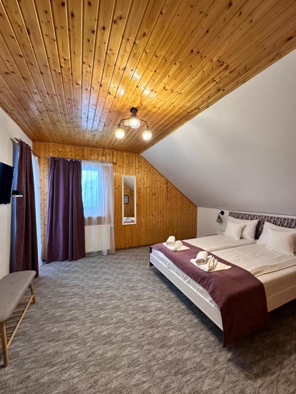 een slaapkamer met een groot bed en een houten plafond bij Red Family Apartments in Păltiniş