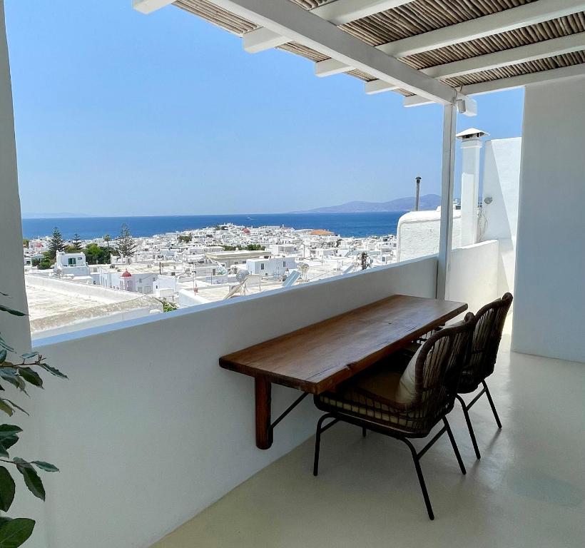 a table and chairs on a balcony with a view of the ocean at Mykonian Starling - Town n' Sunset View Apartment in Mikonos