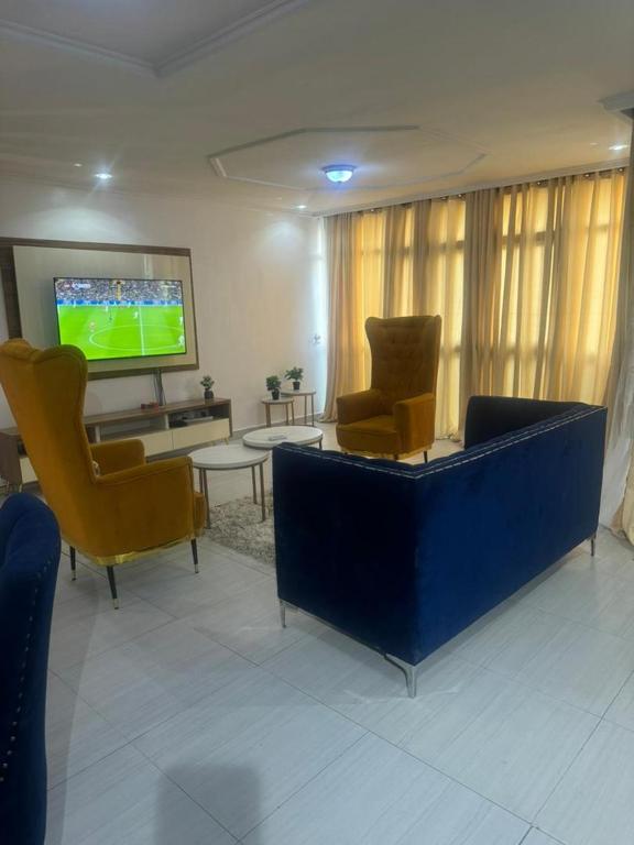 a living room with two chairs and a tv at Merry Villa in Lagos