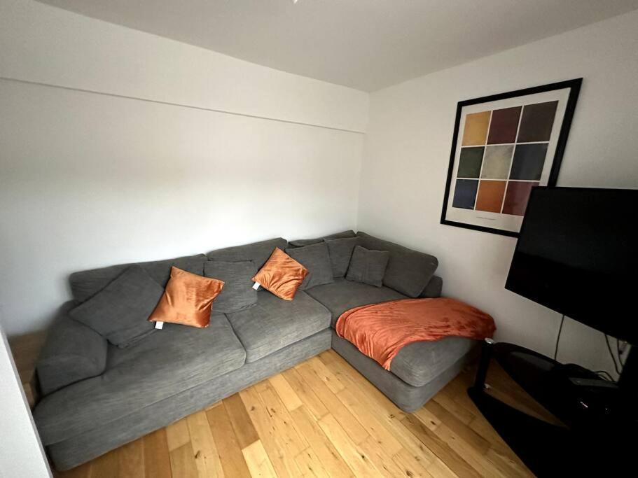 a living room with a gray couch with orange pillows at Risca Inspire in Risca