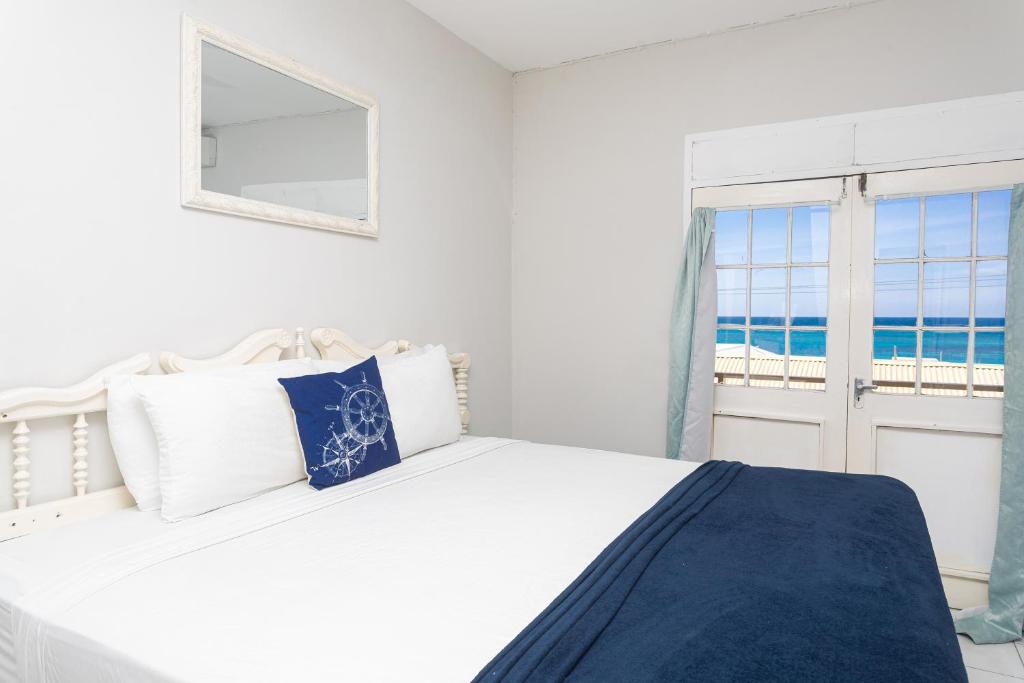 a white bedroom with a bed and a window at Caribic House in Montego Bay