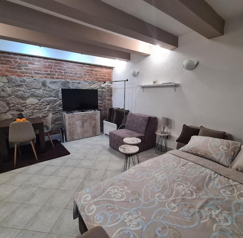 una camera con letto e un soggiorno con parete in pietra di Apartman Sofija Kraljevo a Kraljevo
