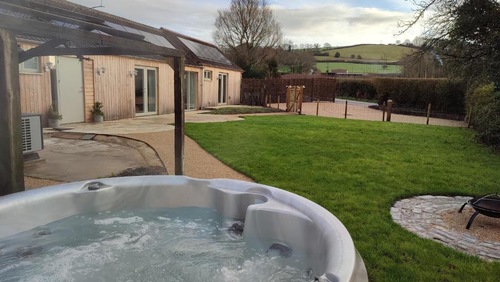 a bath tub in the yard of a house at The Cow Byre - Cotswold retreat with hot tub in Dursley