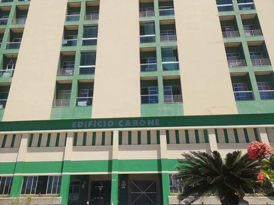 un edificio con una palmera delante de él en Apartamento próximo a praia, en Marataízes