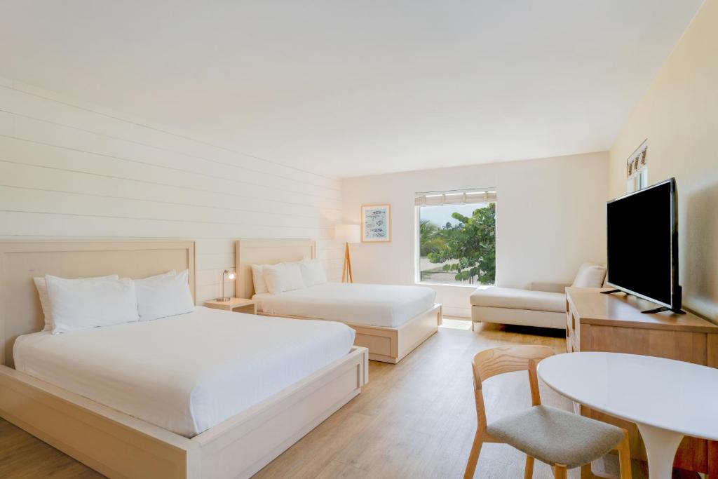a hotel room with two beds and a table and a tv at Fisher Inn Resort & Marina in Islamorada