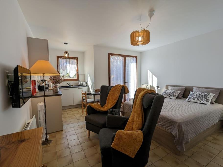 Cet appartement comprend une chambre avec un lit et deux chaises ainsi qu'une cuisine. dans l'établissement Studio - Jardins de Cybèle - Gréoux-les-Bains, à Gréoux-les-Bains