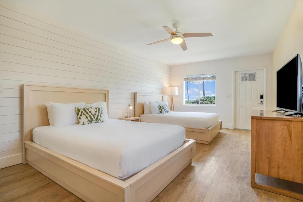 a bedroom with two beds and a flat screen tv at Fisher Inn Resort & Marina in Islamorada