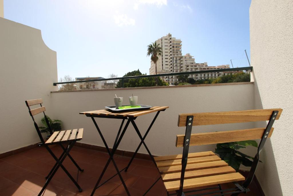 un tavolo e sedie su un balcone con vista sulla città di Appartement avec piscine - Albufeira ad Albufeira