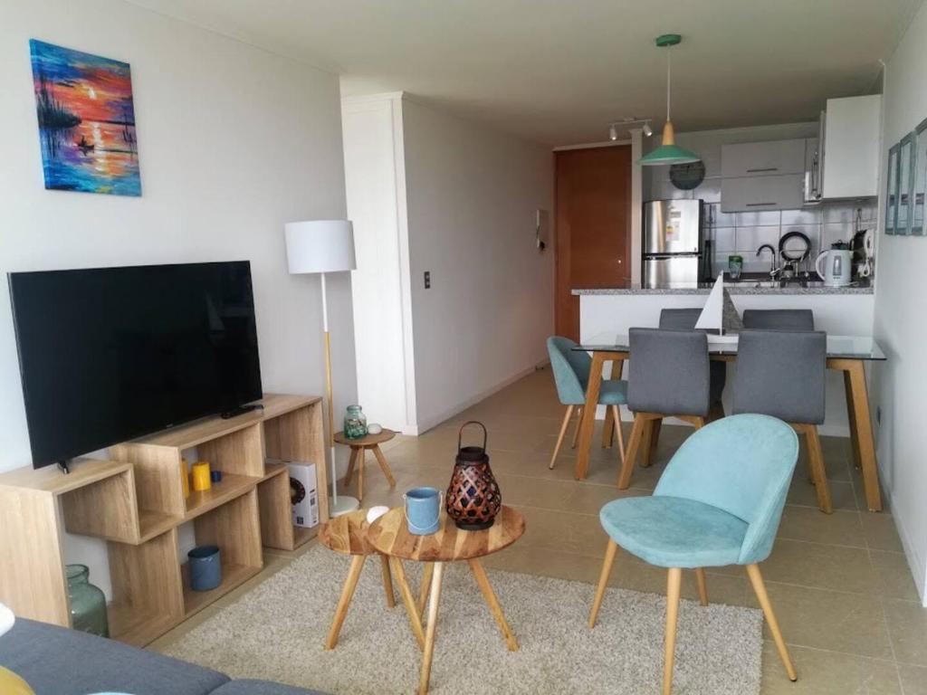 a living room with a television and a table and chairs at Departamento playa La Herradura in Coquimbo