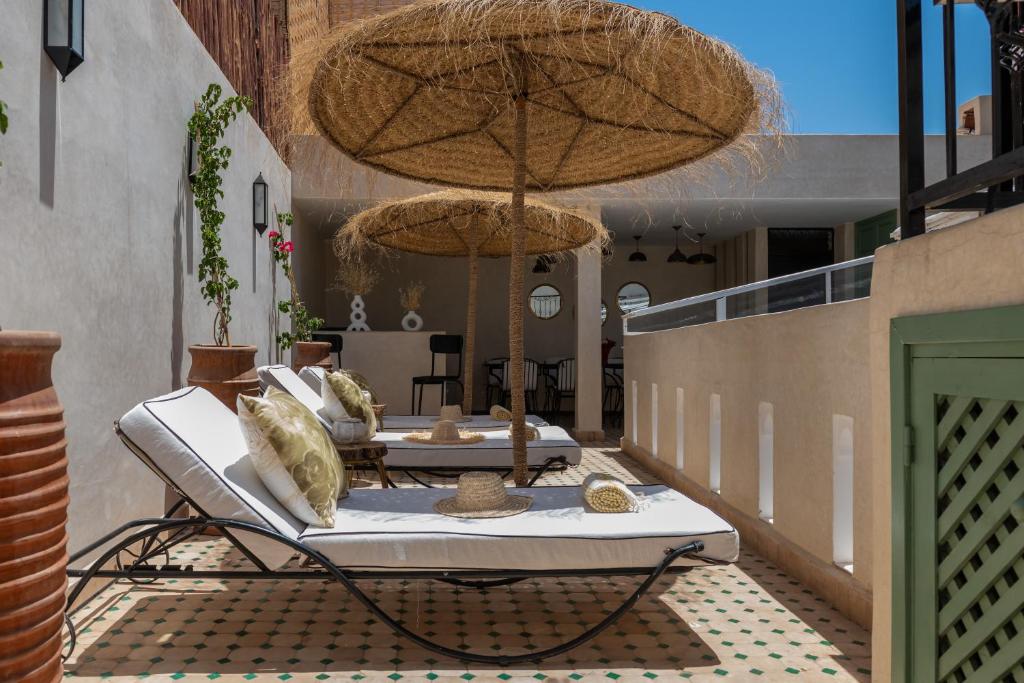 2 tumbonas y sombrillas en un patio en Riad Kasbah El Mamoune en Marrakech