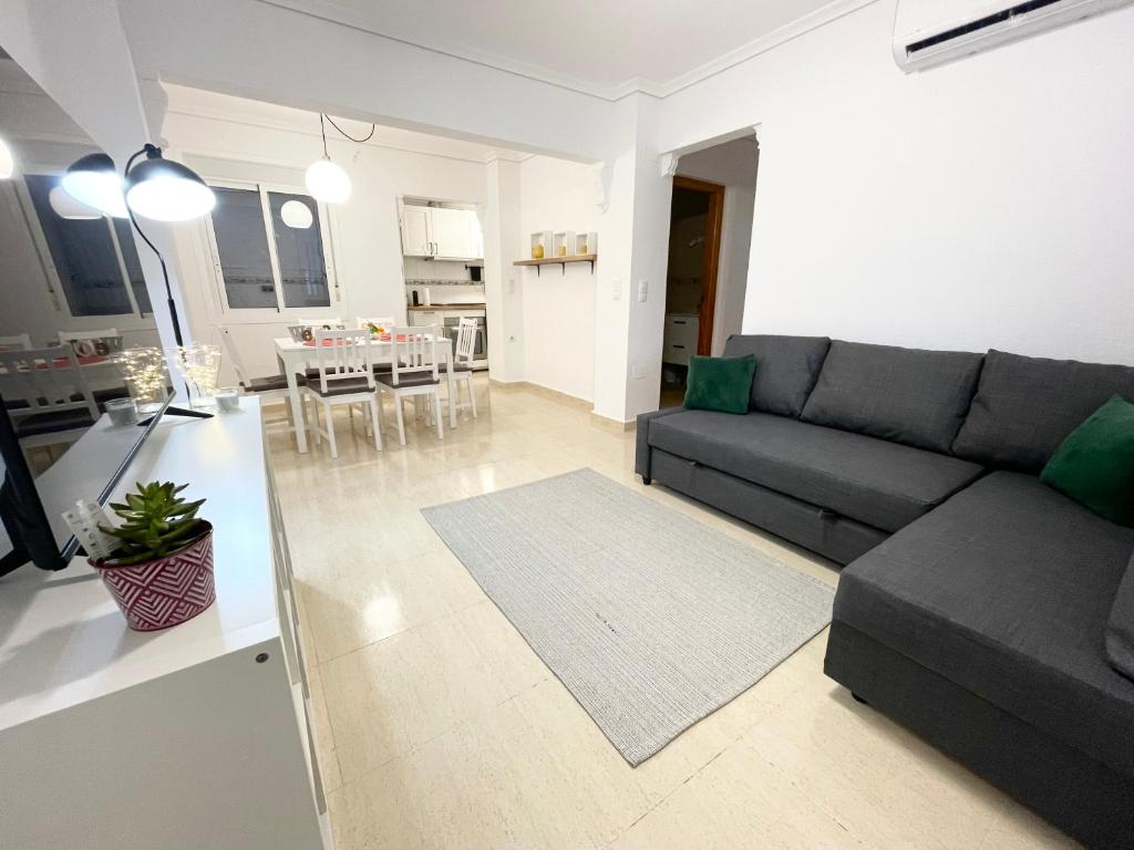 sala de estar con sofá gris y cocina en Villa Dulce, en Gran Alacant