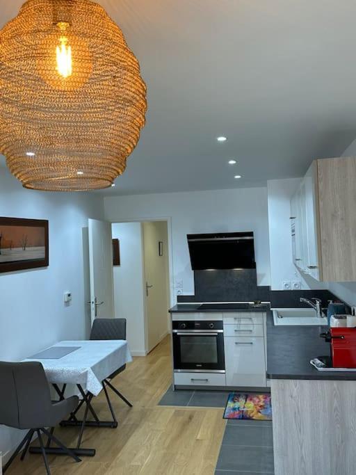 une cuisine avec une cuisinière et une table avec des chaises dans l'établissement Appartement Neuf de 40 M2 à Issy-Les-Mx / Paris 15, à Issy-les-Moulineaux