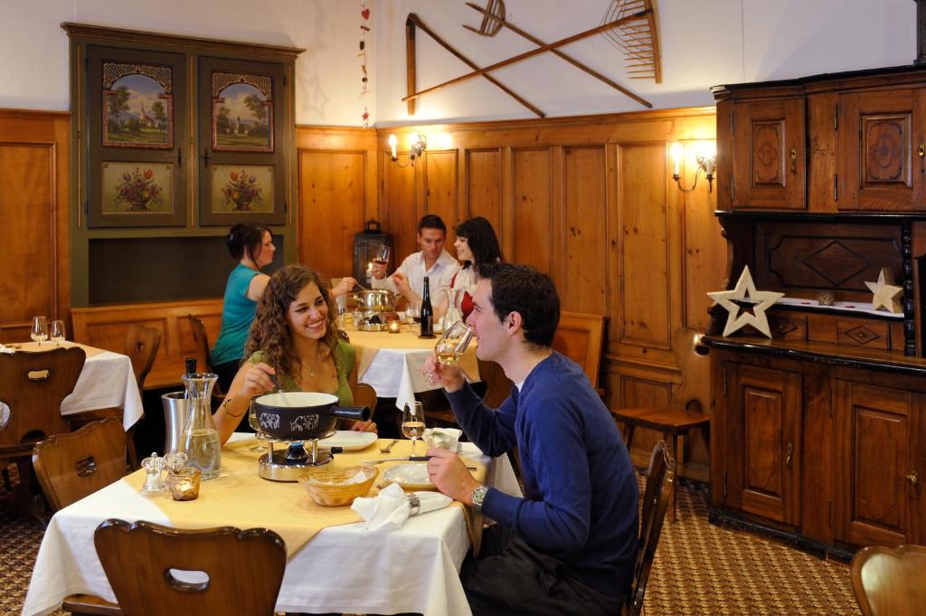 a group of people sitting at a table in a restaurant at Hotel Schweizerhof in Engelberg