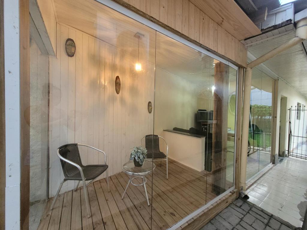 a screened in porch with two chairs and a table at Suíte 2 com sala in Lages