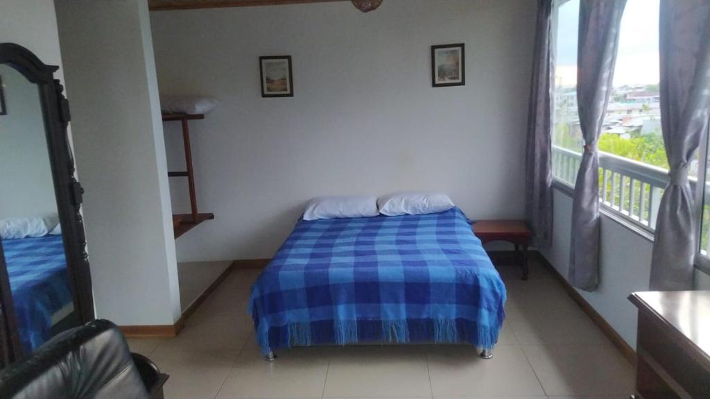 a bedroom with a bed with a blue checked blanket at Apartamento pequeño, acogedor, 1 habitación, vista a zonas verdes, English in Calarcá