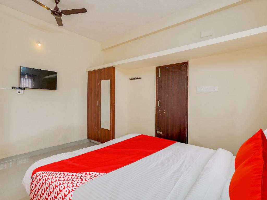 a bedroom with a red and white bed and a tv at OYO Flagship Srinivasa Residency in Chennai