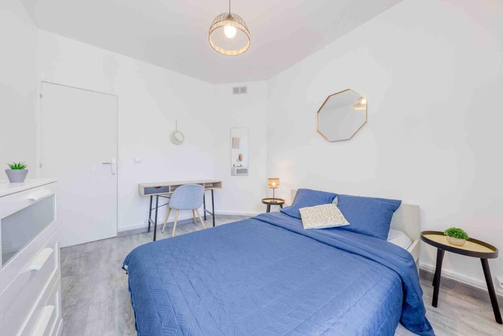 a white bedroom with a blue bed and a table at Appartement Cosy I Proche de la Porte de Versailles Paris in Malakoff