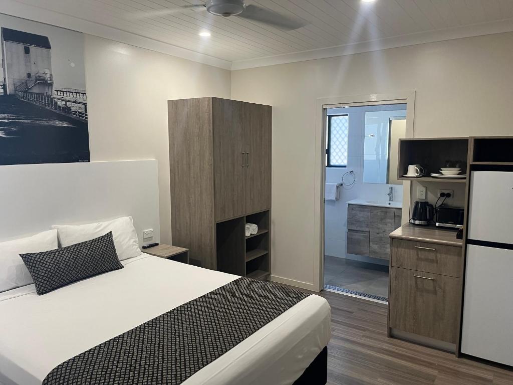 a bedroom with a bed and a refrigerator and a kitchen at Lucinda Village in Lucinda