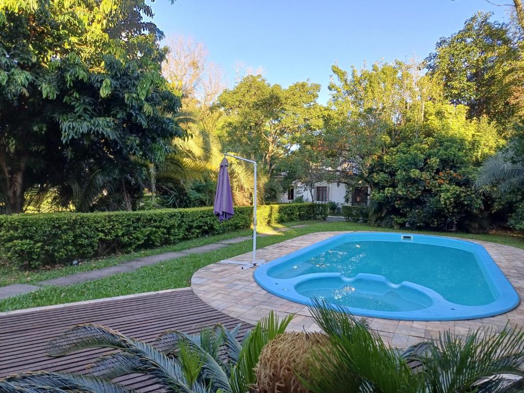 a swimming pool in a yard with a umbrella at Chácara Rosa Cortiana in São Gabriel