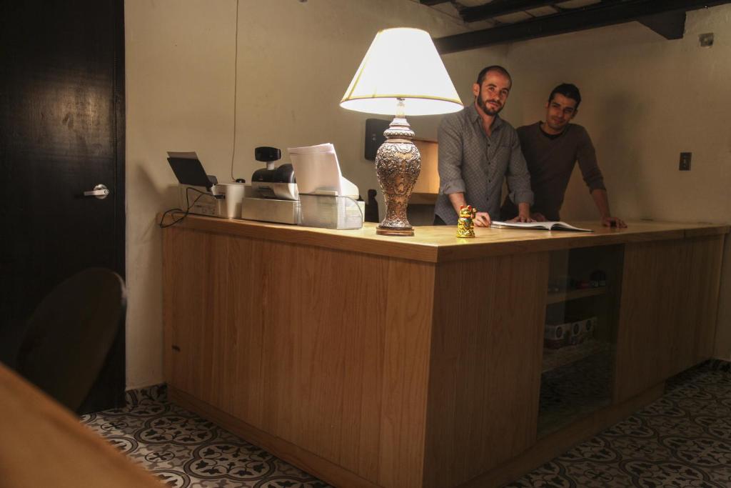 a man and a woman sitting at a desk in a kitchen at Capsule Hostel in Mexico City