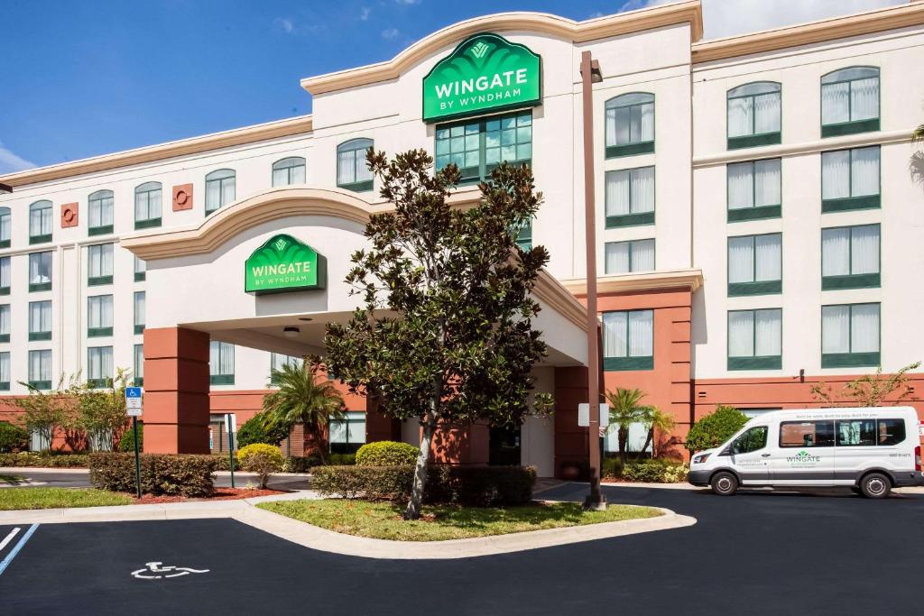 a hotel with a van parked in front of it at Wingate By Wyndham - Orlando International Airport in Orlando