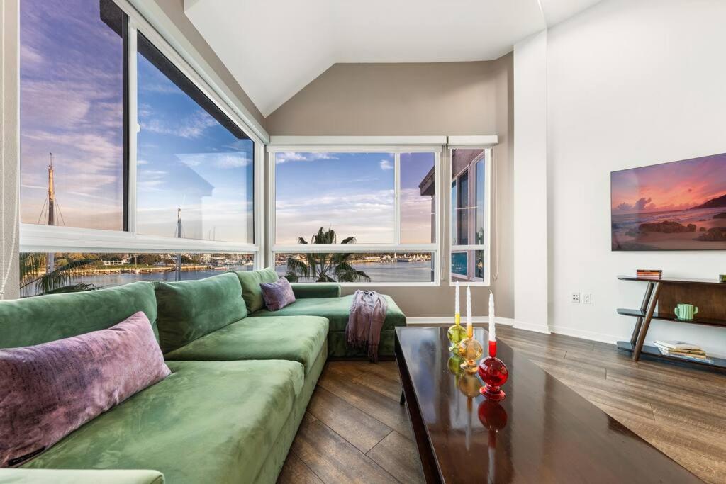 ein Wohnzimmer mit einem grünen Sofa und großen Fenstern in der Unterkunft Skyline Oasis: Luxe 3-Floor Waterfront Penthouse in Los Angeles