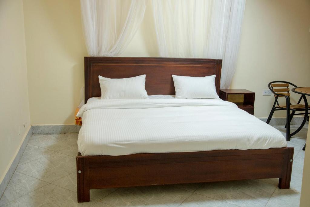 ein Bett mit weißer Bettwäsche und Kissen in einem Schlafzimmer in der Unterkunft Eziana palm hotels 