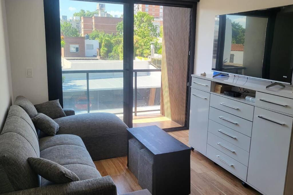 Hermoso apartamento en pocitos في مونتيفيديو: غرفة معيشة مع أريكة وتلفزيون
