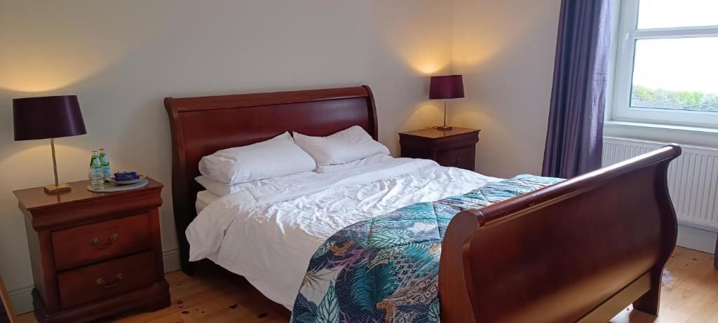 a bedroom with a bed and two night stands and a window at Harbor View in Valentia Island