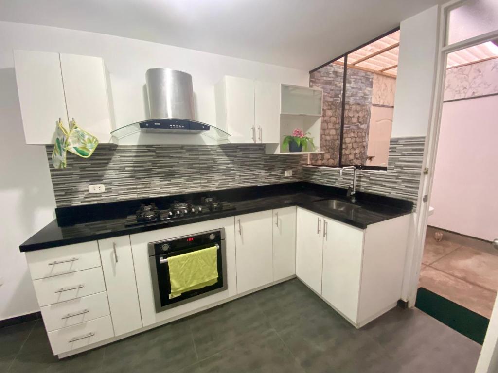 a kitchen with white cabinets and a stove top oven at Acogedora Casa cerca a la playa in Pisco