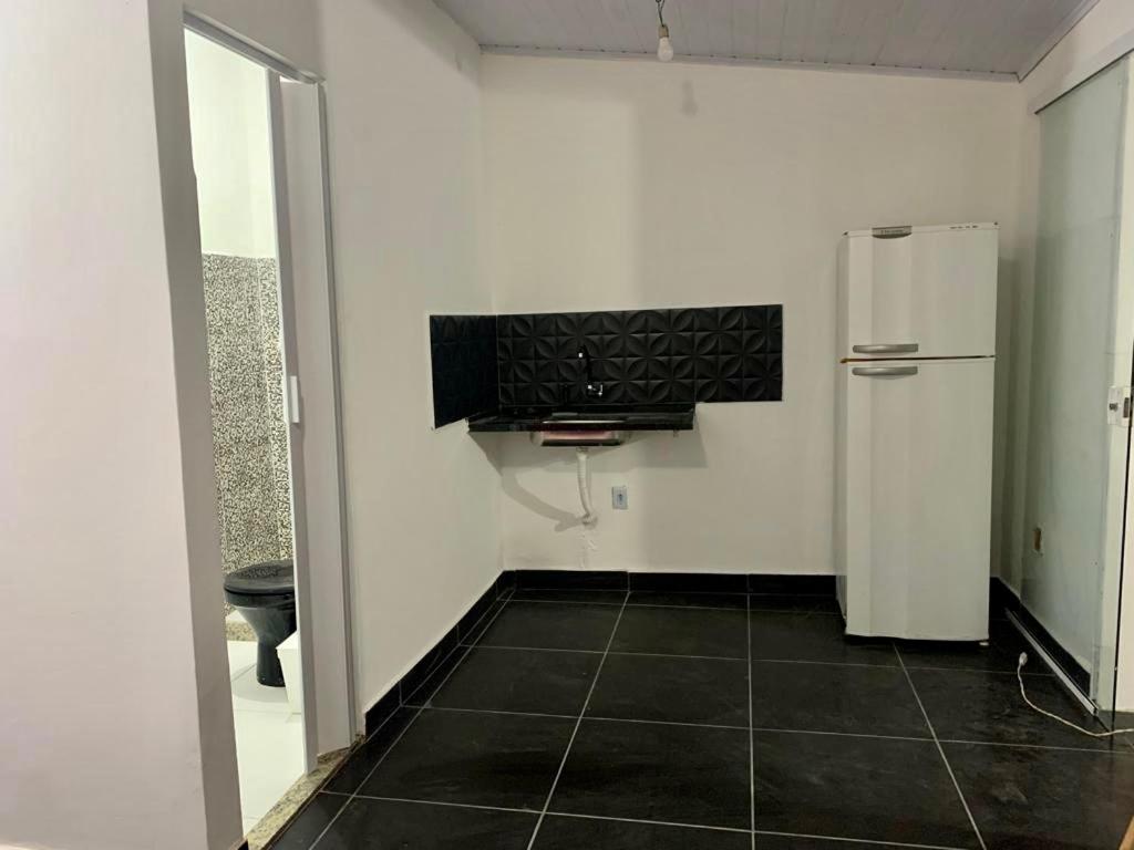 a kitchen with a refrigerator and a black tile floor at Kit net linda e aconchegante in Cabo Frio