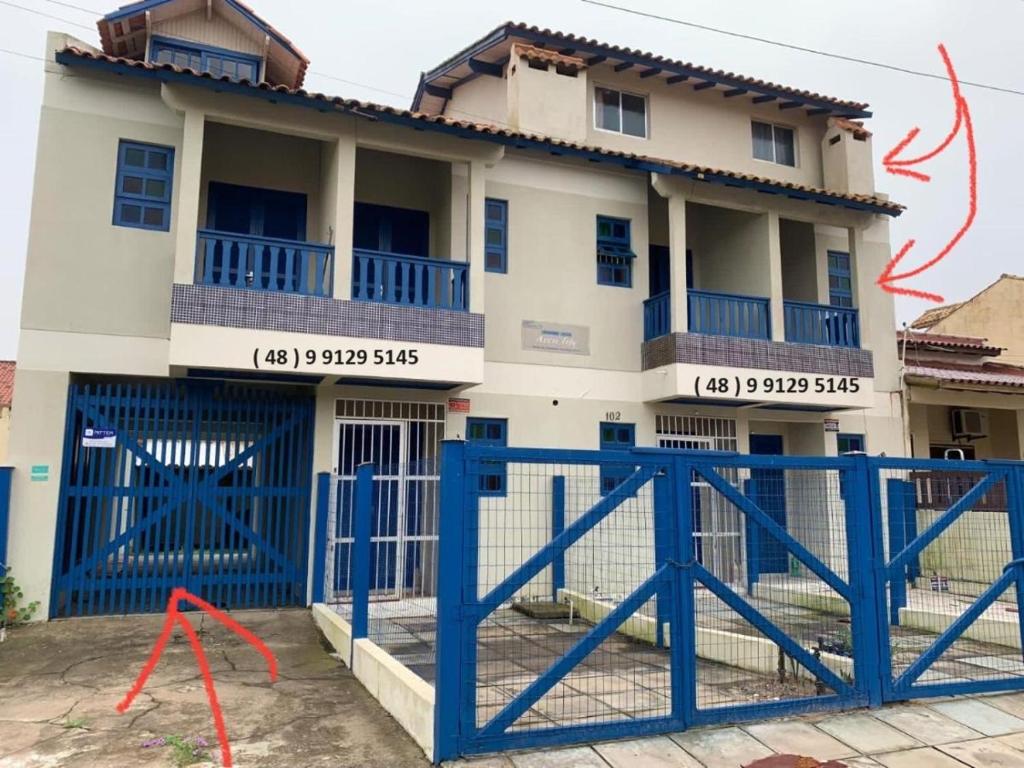 ein Haus mit blauen Toren davor in der Unterkunft Apartamento de 6a8 P Churrasqueira in Cidreira
