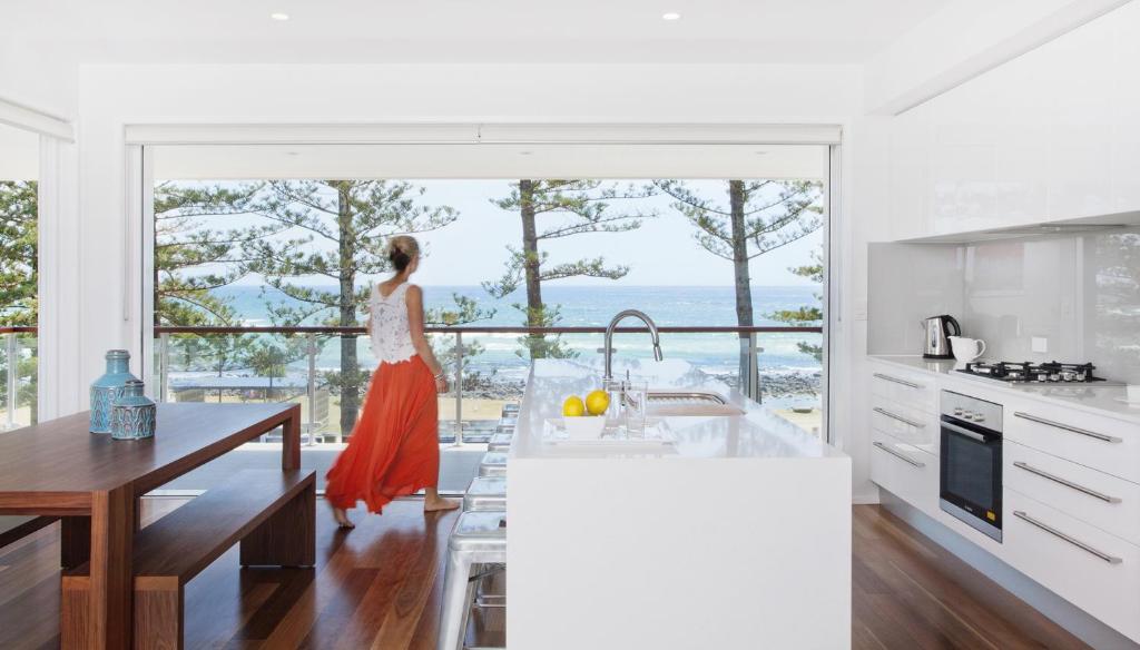 a woman standing in a kitchen looking out at the ocean at Bujerum Apartments on Burleigh in Gold Coast