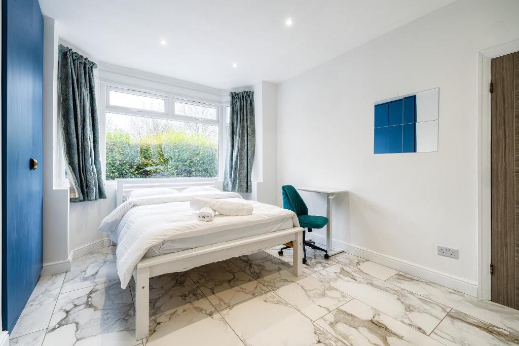 een witte slaapkamer met een bed en een raam bij Luxurious 2 bedroom flat with parking and garden, 5 mins walk to train station and bus stop opposite property in Londen