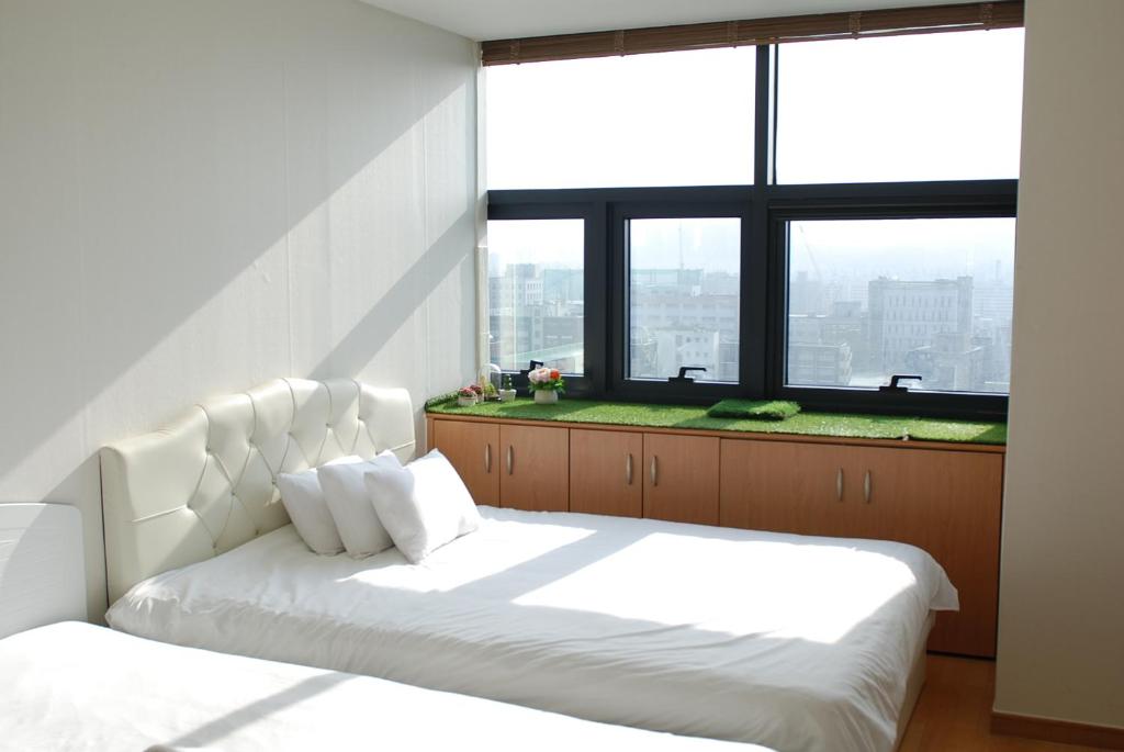 1 Schlafzimmer mit 2 weißen Betten und einem großen Fenster in der Unterkunft Samsung Coex Daechi Gangnam House G in Seoul