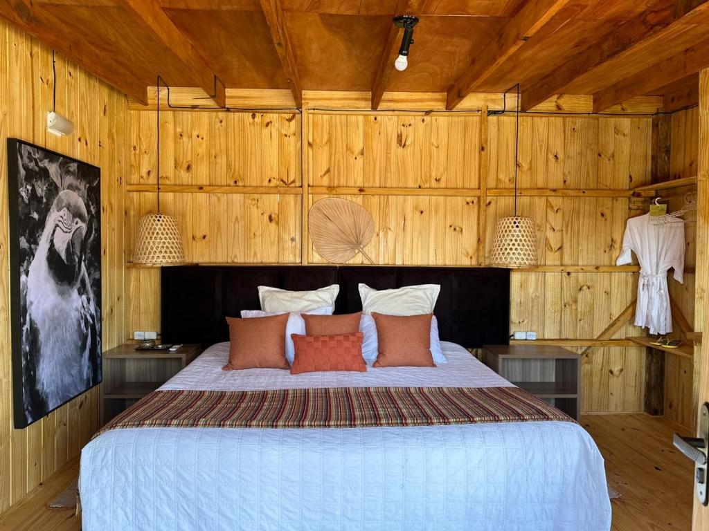 a bedroom with a large bed with wooden walls at BRASILEIRÍSSIMO POUSADA in Punta Del Diablo