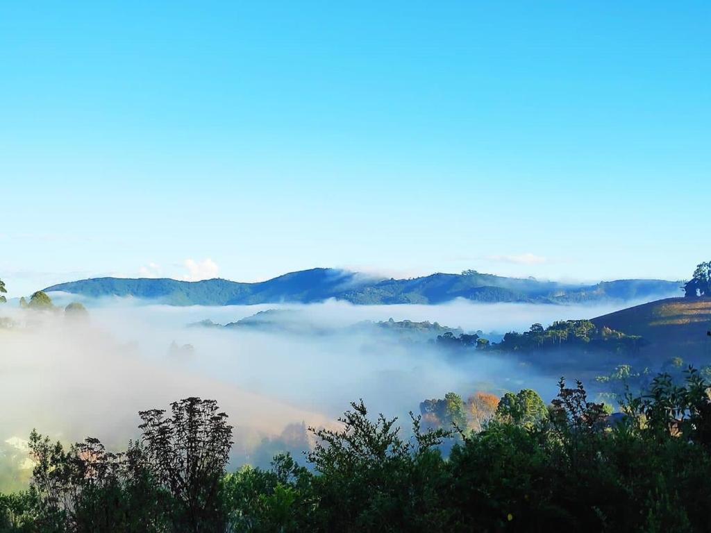 - une vue sur une vallée brumeuse avec des arbres et des montagnes dans l'établissement Chales Boa Vista, à Monte Verde