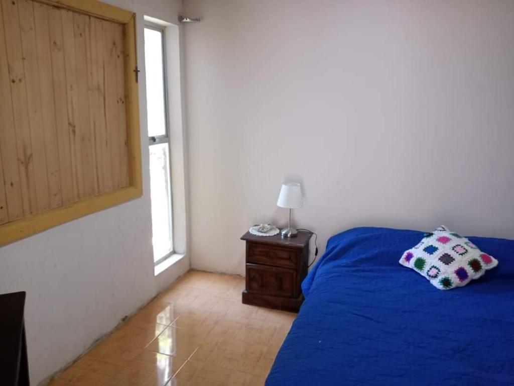 Un dormitorio con una cama azul y una ventana en Casa de campo, en Pichilemu