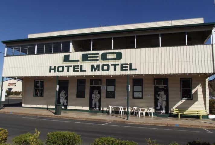 a hotel motel with tables and chairs on a street at Leo Hotel Motel in Clermont