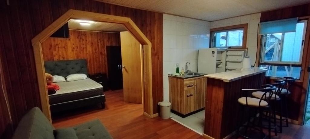 een kleine kamer met een bed en een keuken bij JANICO CABAÑAS in Loncoche